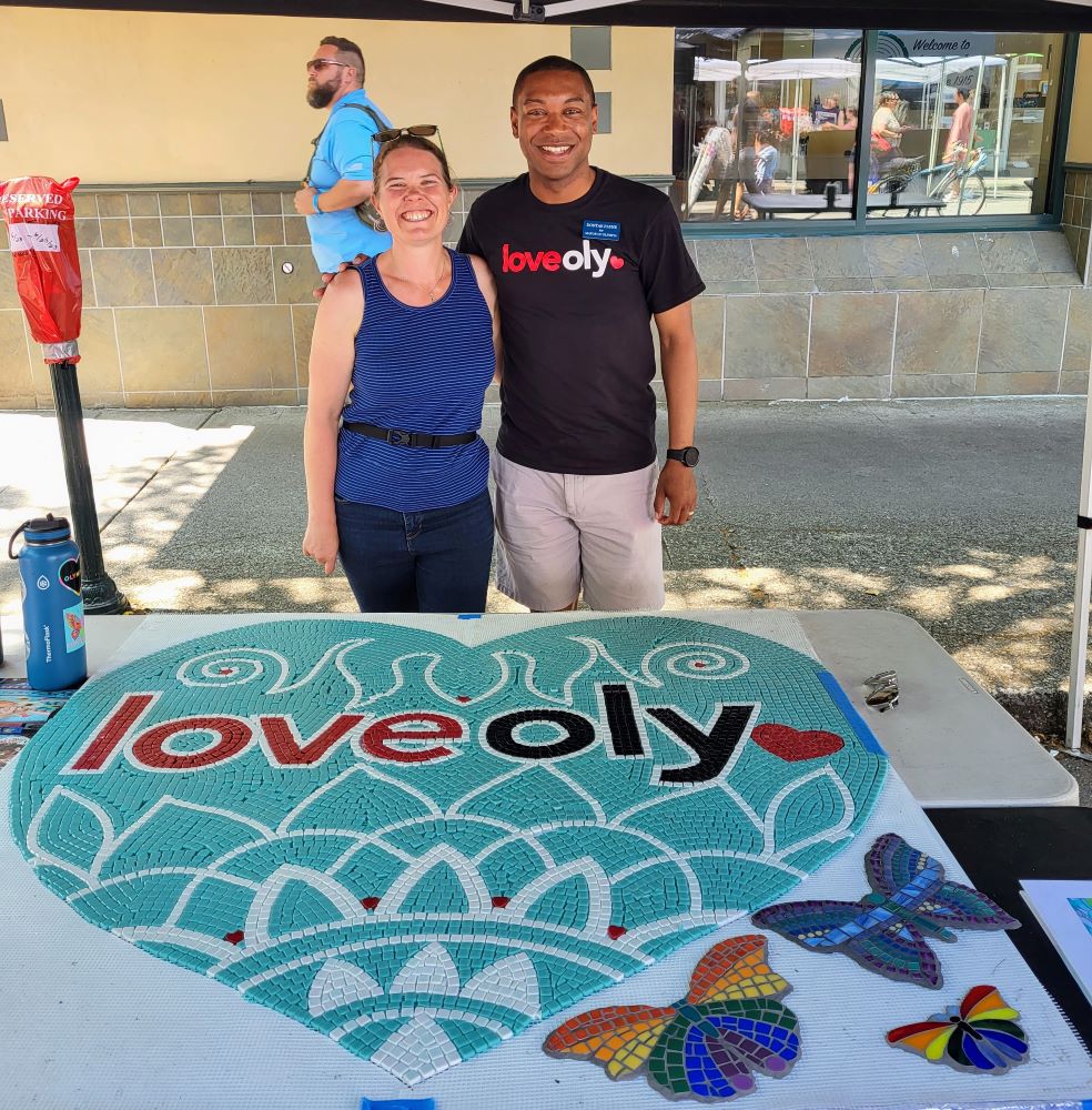 Two people standing behind a tile heart that says LoveOly