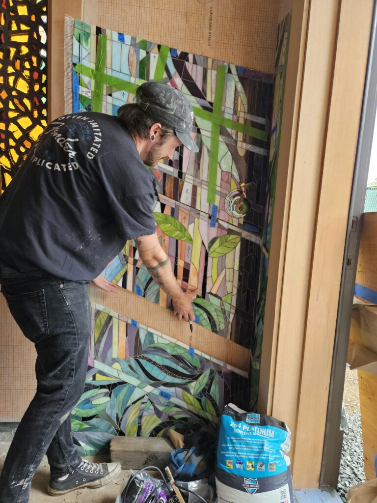 Austin Harris helping to install a stained glass mosaic panel.